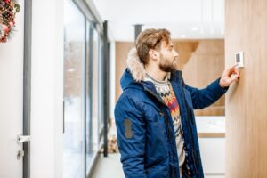 Cold Man Adjusting Smart Thermostat Screen